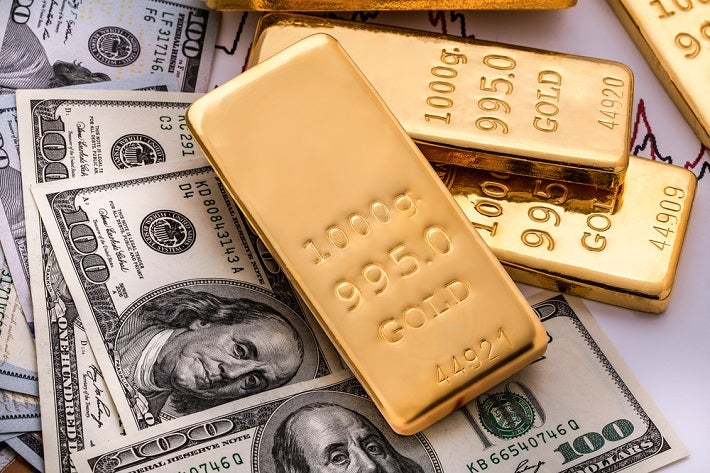 Some dollar bills and gold bars are shown